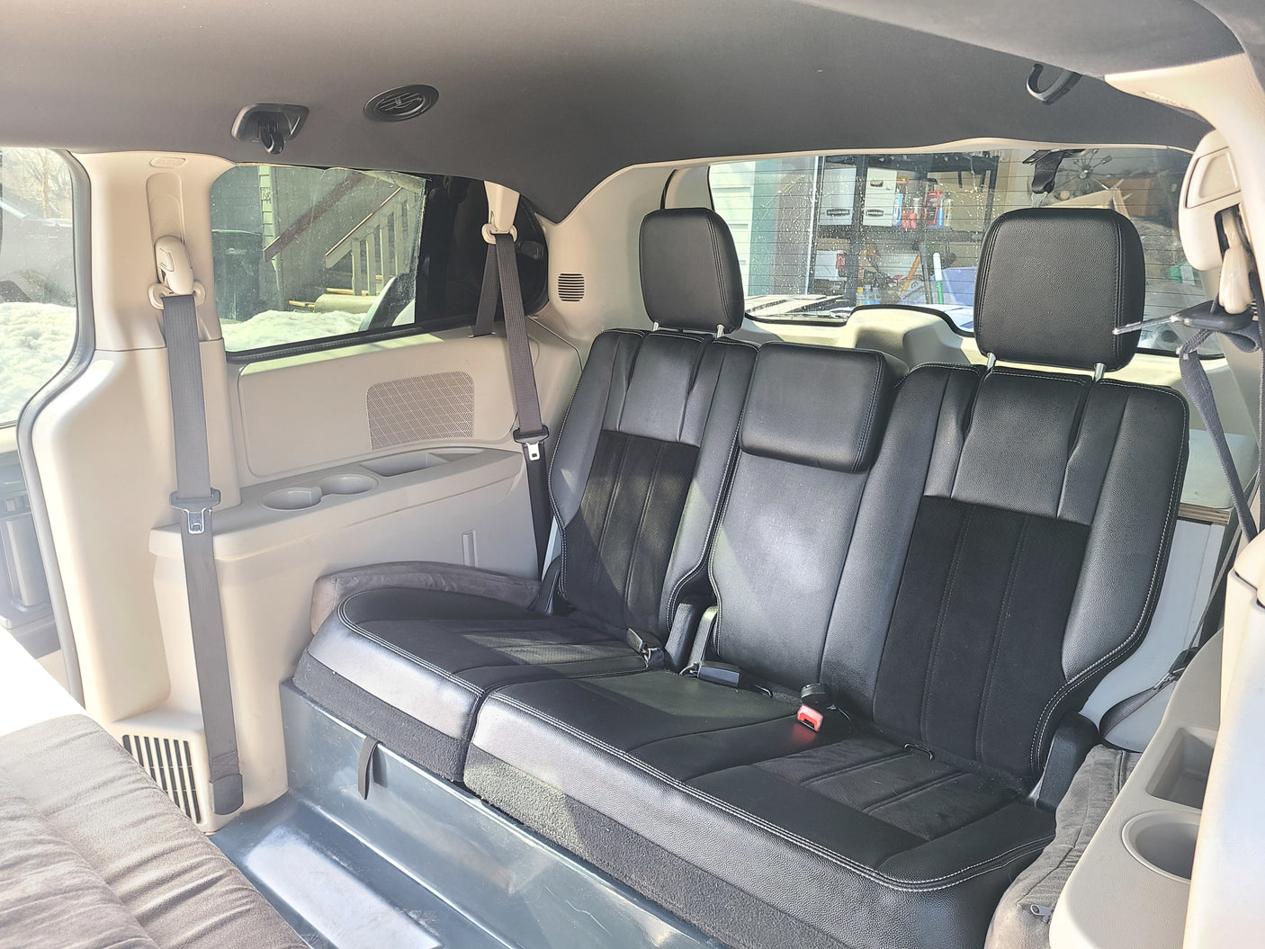 Experience comfort in this RV rental! Spacious van interior with black passenger seats, seatbelts, and a versatile sleeping area.