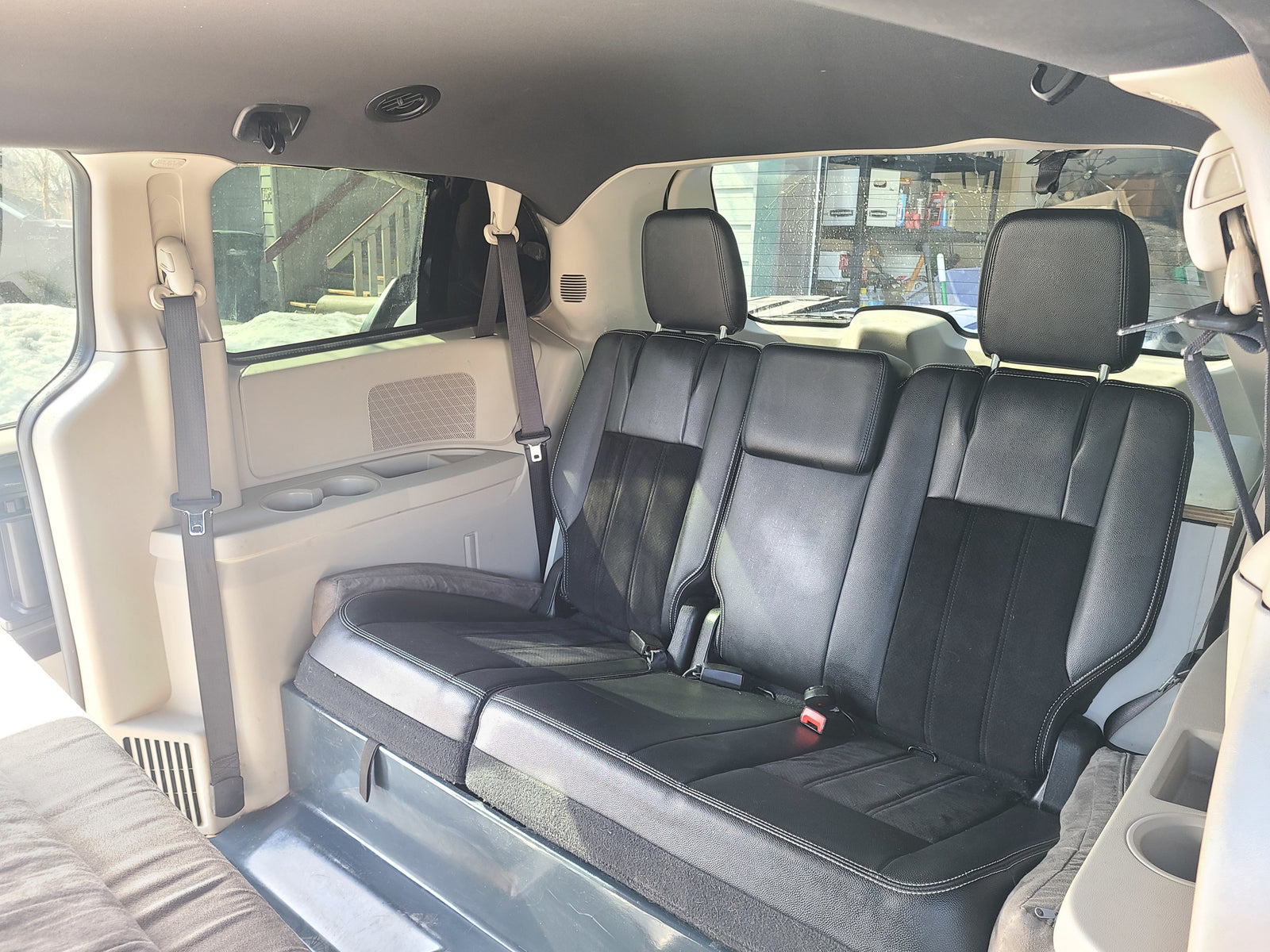 Experience comfort in this RV rental! Spacious van interior with black passenger seats, seatbelts, and a versatile sleeping area.