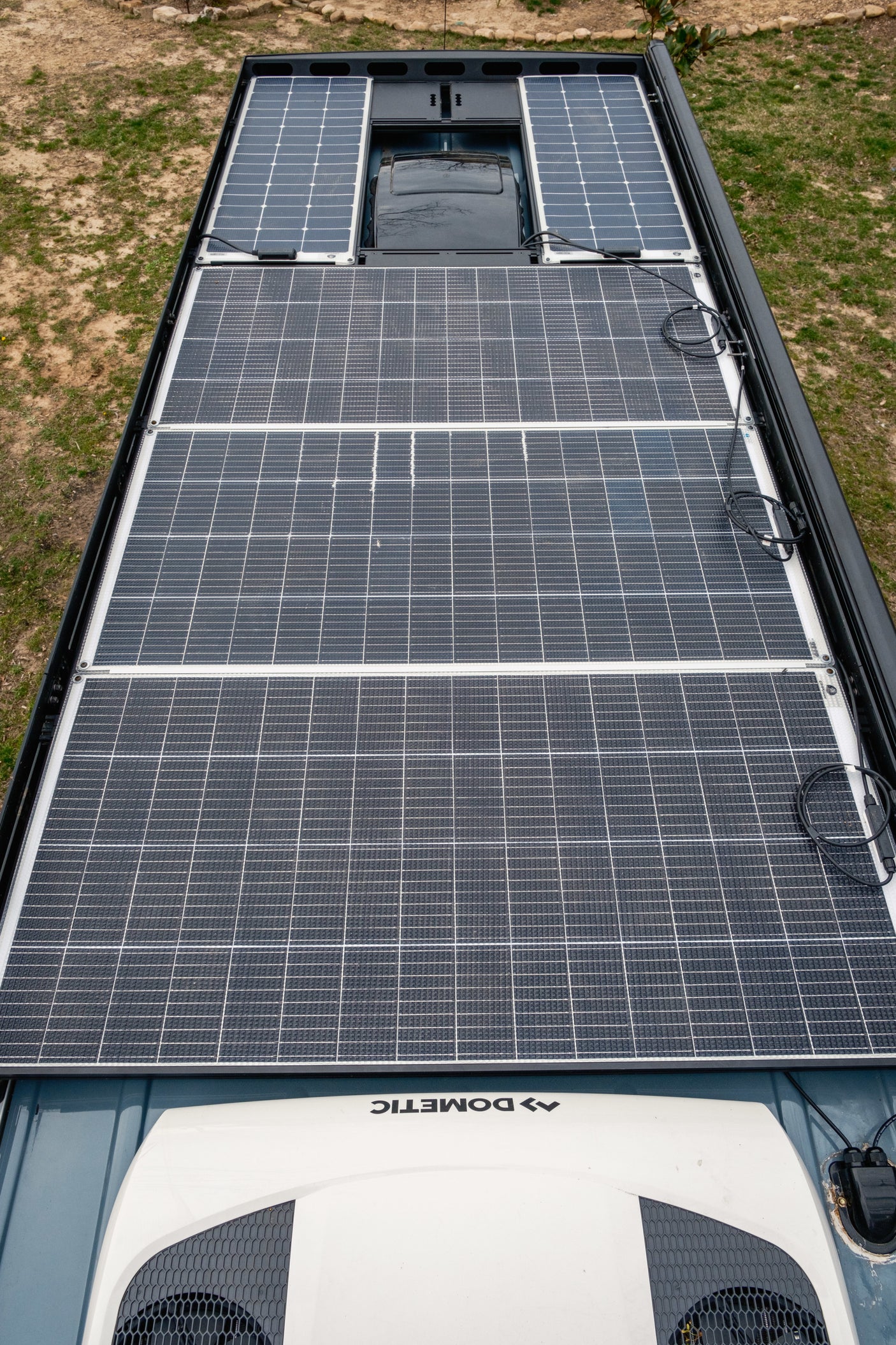 High angle shot of an RV rental roof with extensive solar panels and a Dometic AC unit for off-grid comfort.
