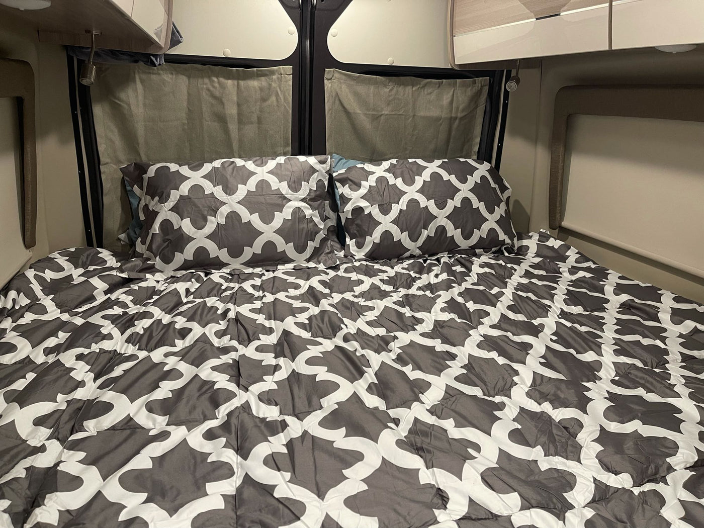 Inside an RV rental: a cozy bed with gray and white patterned comforter and pillows, ready for restful travel. — photo 9