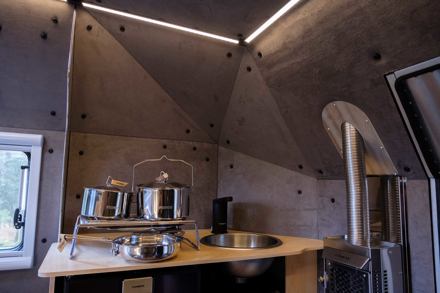 Modern RV rental kitchen with Primus pots, Dometic sink, Dickinson stove. Compact & complete.