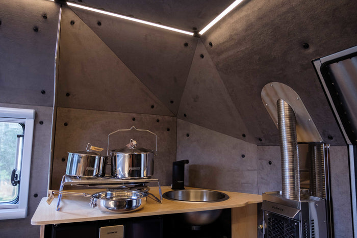 Modern RV rental kitchen with Primus pots, Dometic sink, Dickinson stove. Compact & complete.
