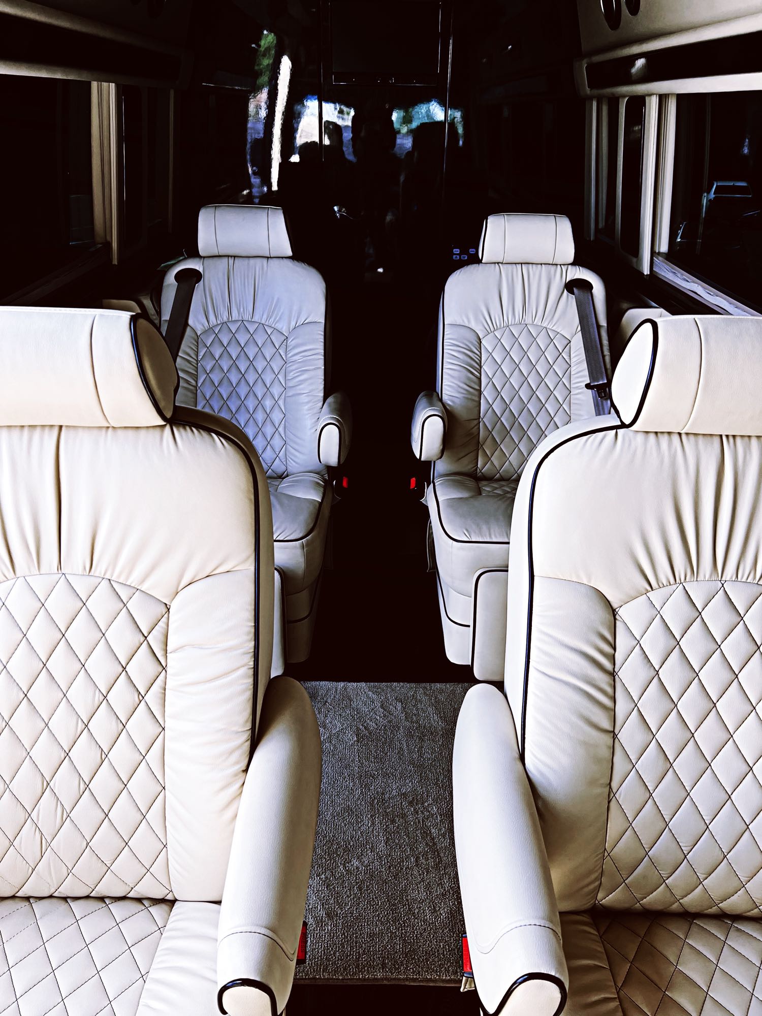 bright lights and elegant strip lighting.|Plush custom RV rental interior: two cream captain's chairs with footrests