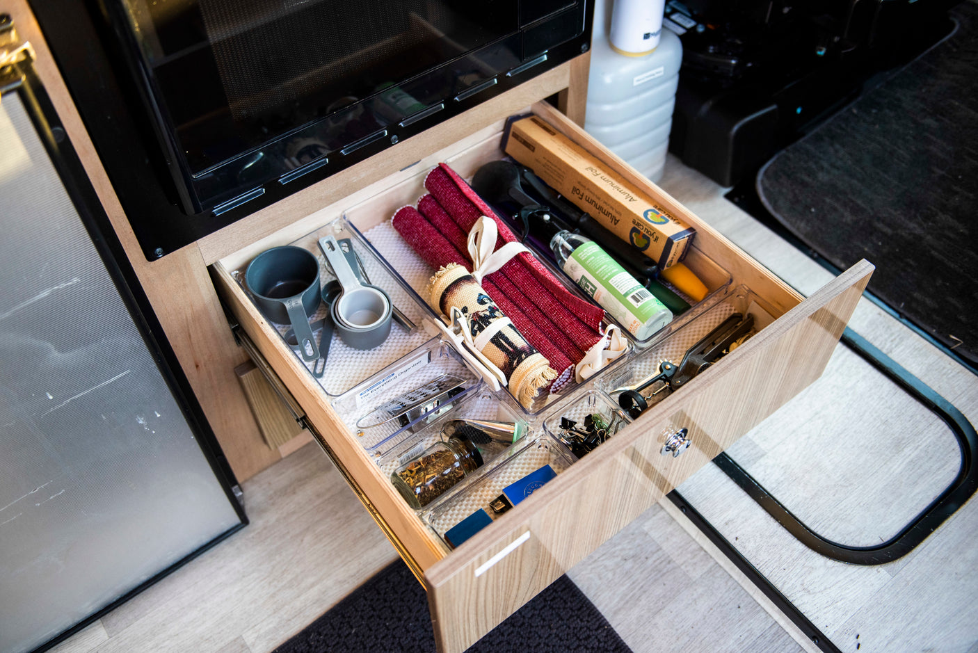 RV rental kitchen drawer, perfectly organized with cooking essentials: foil, measuring cups, and various utensils.