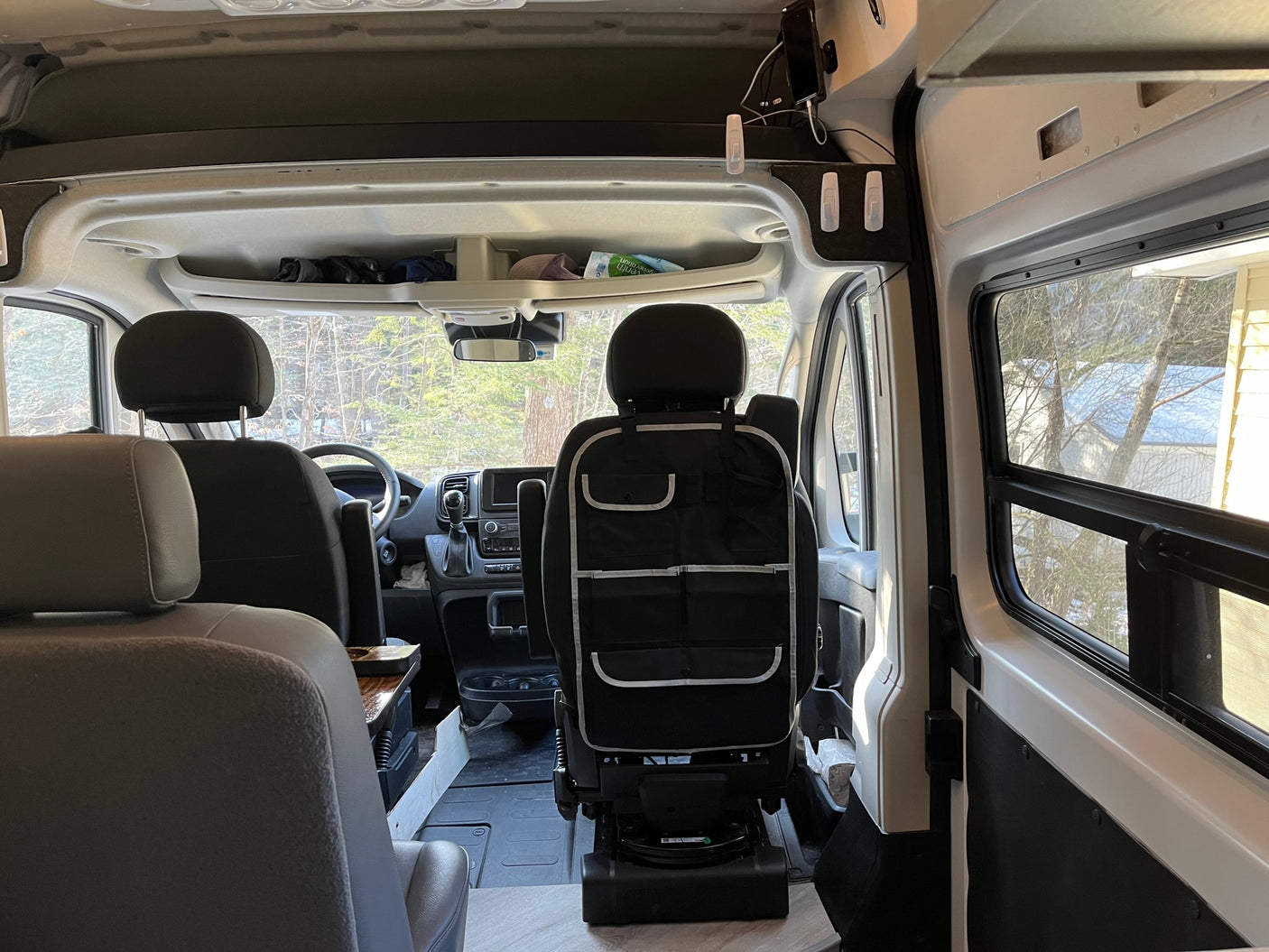 Inside this spacious RV rental, the front cabin, dashboard, and seats are visible, with overhead storage and a seat organizer.