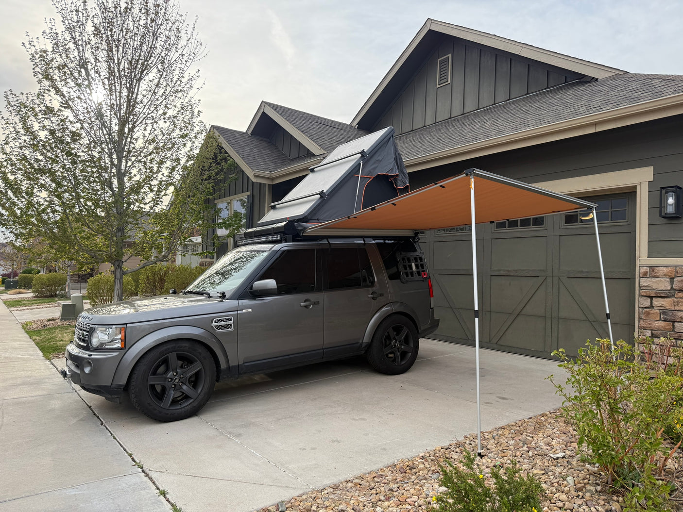 Gray Land Rover SUV with rooftop tent & side awning, an ideal rv rental alternative for overlanding and camping.