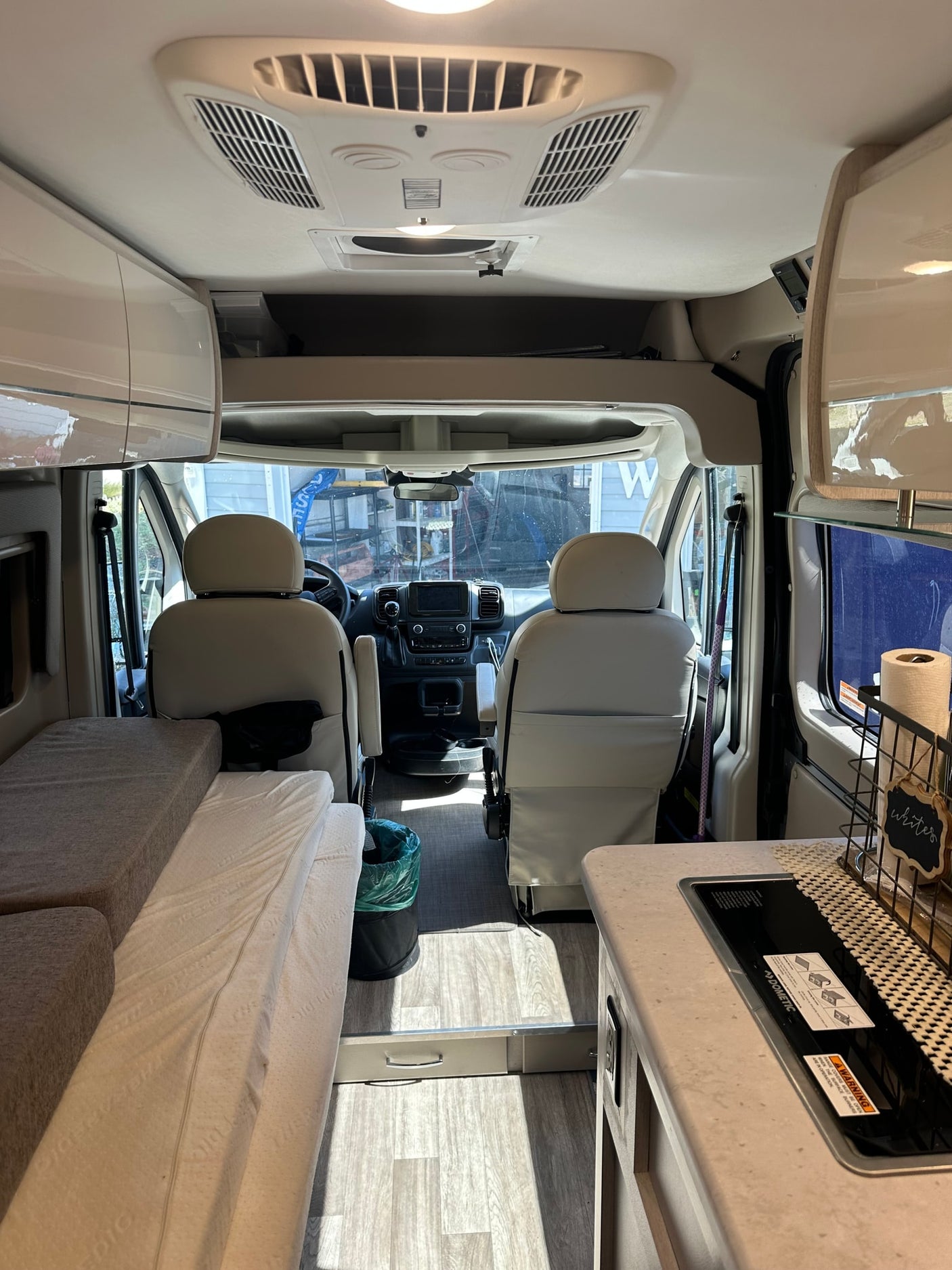 This RV rental interior offers a view of the cockpit, bed/seating, and compact kitchen, ready for your next adventure.