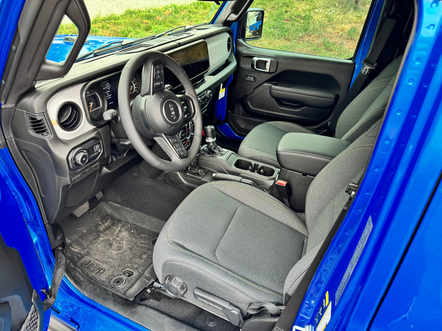 Bright blue Jeep interior: dashboard, steering wheel, and cloth seats, ideal for adventures or complementing an rv rental trip.