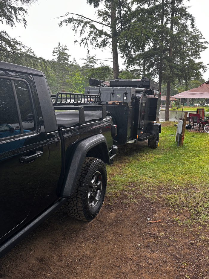 and overland trailer with rooftop tent.|A black Jeep Gladiator towing an overland camping trailer