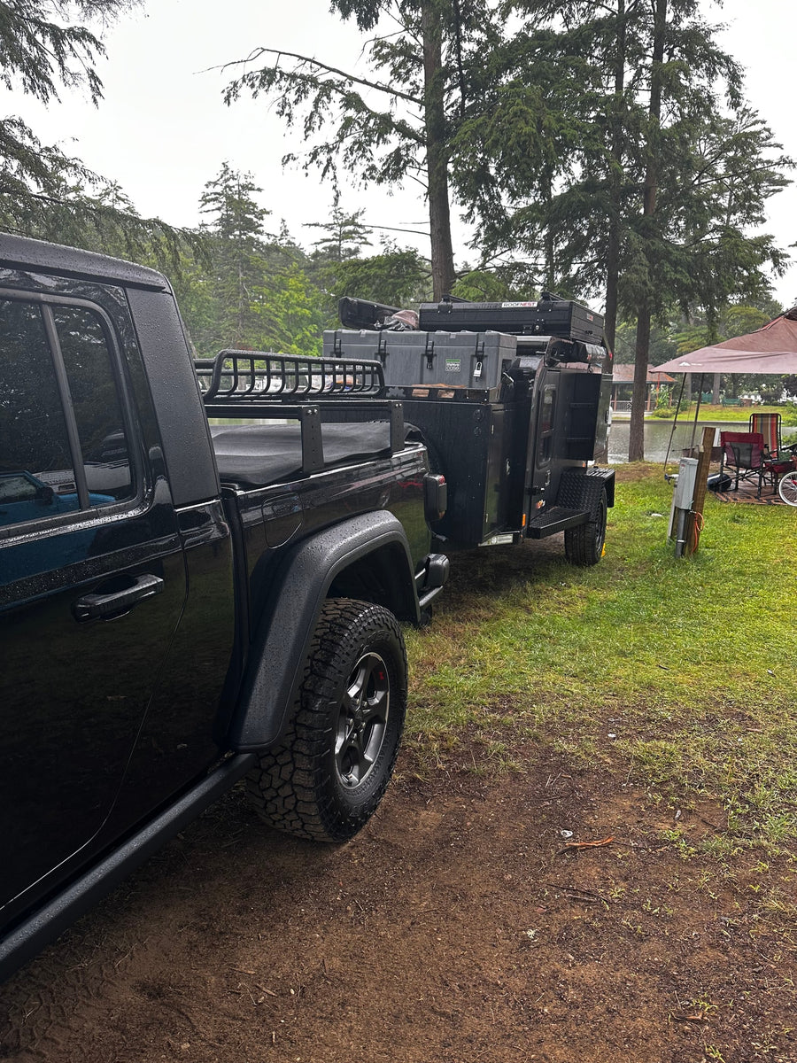 and overland trailer with rooftop tent.|A black Jeep Gladiator towing an overland camping trailer