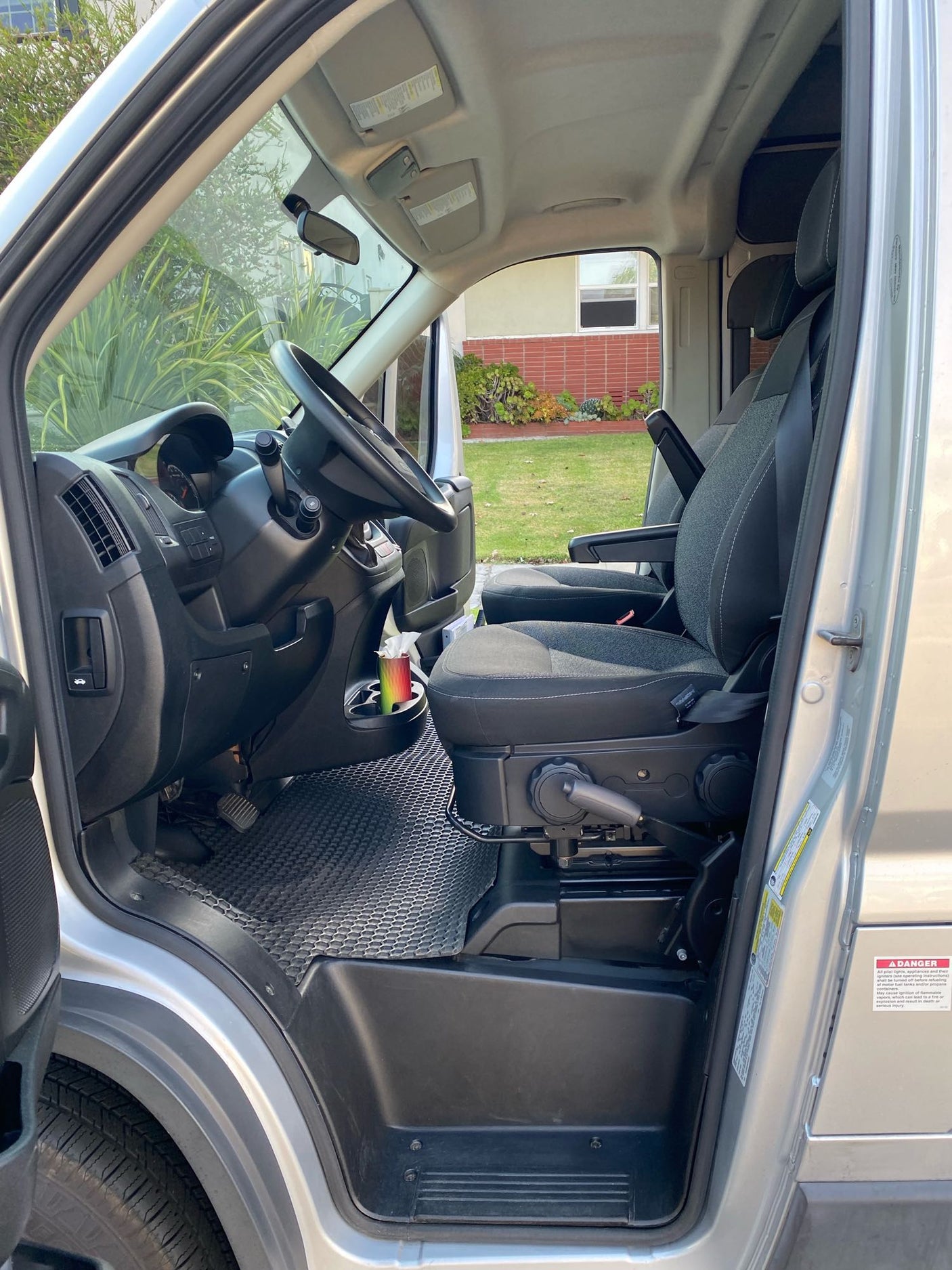 Step inside this RV rental! View of the driver's seat, steering wheel, and dashboard in a spacious camper van.