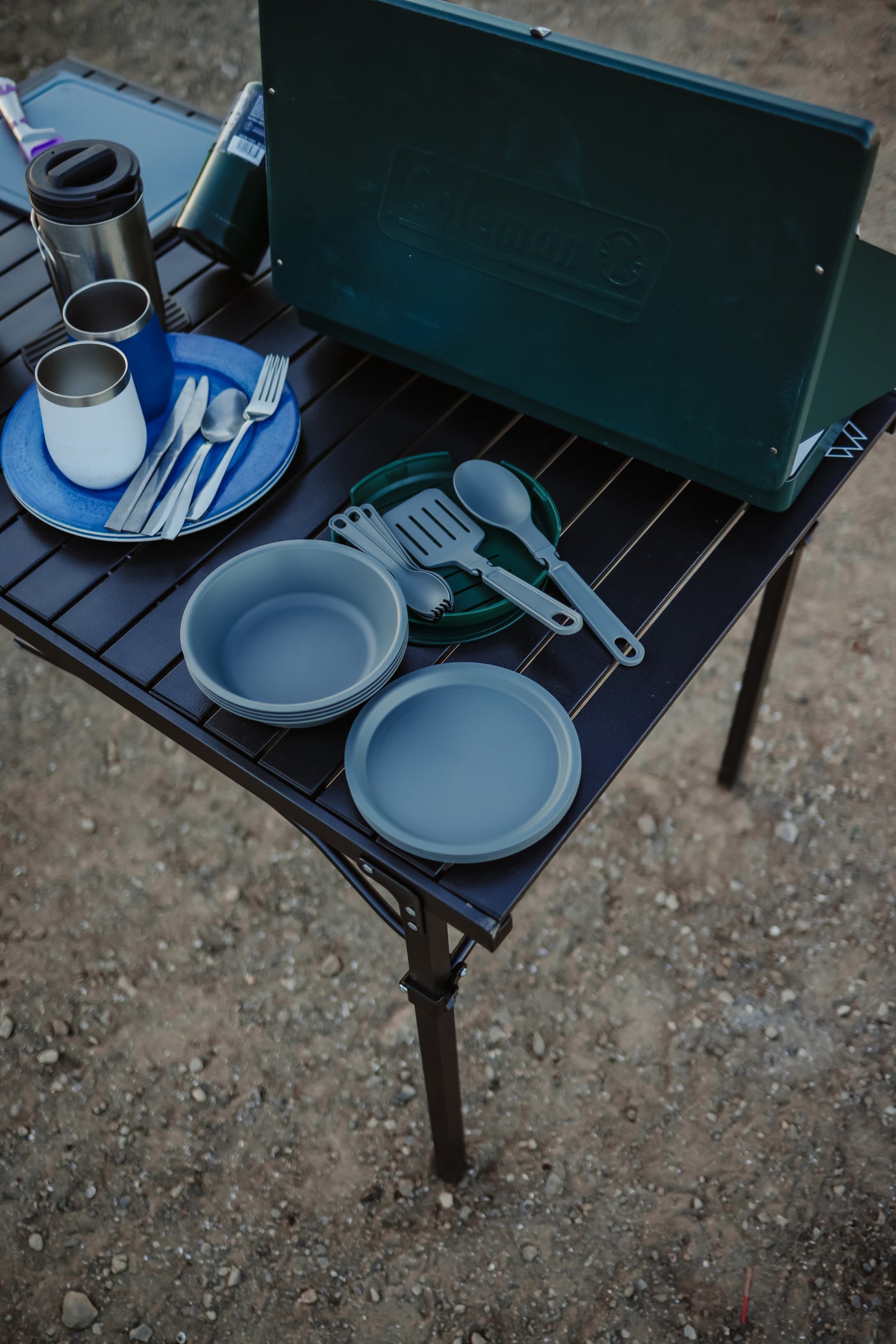 RV rental adventure: Coleman stove, camping dishes, & travel mugs on a portable table. Everything for outdoor cooking.