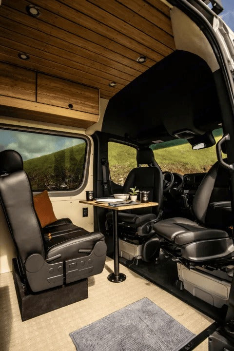 Experience comfort in this rv rental. A modern camper van interior with swivel seats, dining table, and wood ceiling.