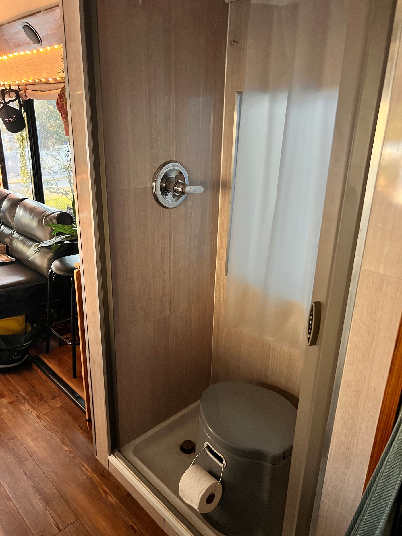 Inside an RV rental: a compact bathroom featuring a shower with controls, a portable toilet, and a roll of toilet paper. — photo 17
