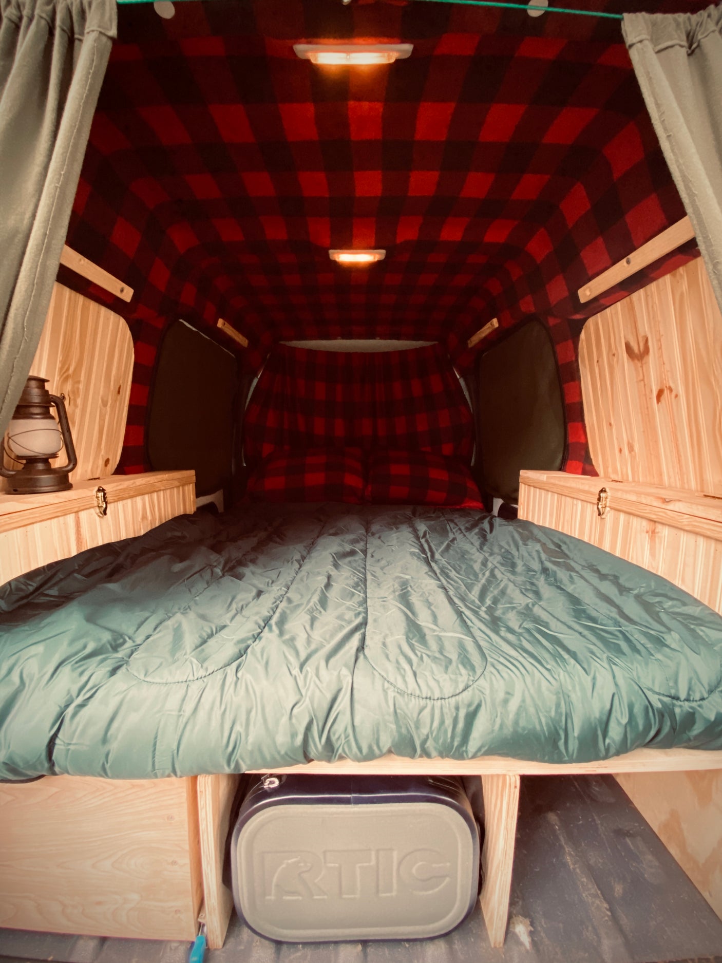 Experience comfort in this **rv rental**! Features a cozy red plaid interior, full bed, wood trim, and cooler storage.