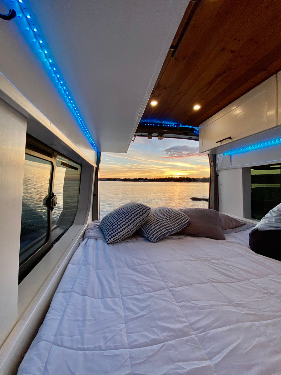 revealing its modern kitchen and a person inside. Solar panels are on the roof.|Cozy camper van interior for rv rental