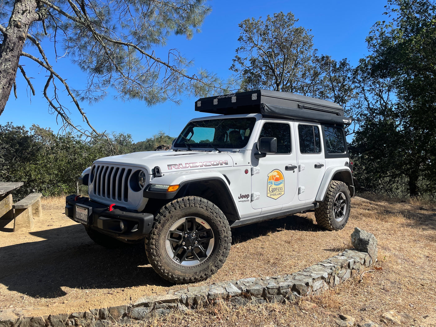 White Jeep Wrangler Rubicon 4x4 with rooftop tent, perfect for an RV rental overlanding or camping trip.