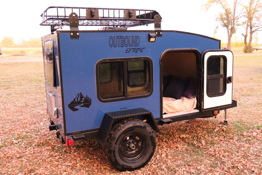 and a window revealing nature outside.|This blue Outbound Extreme teardrop camper