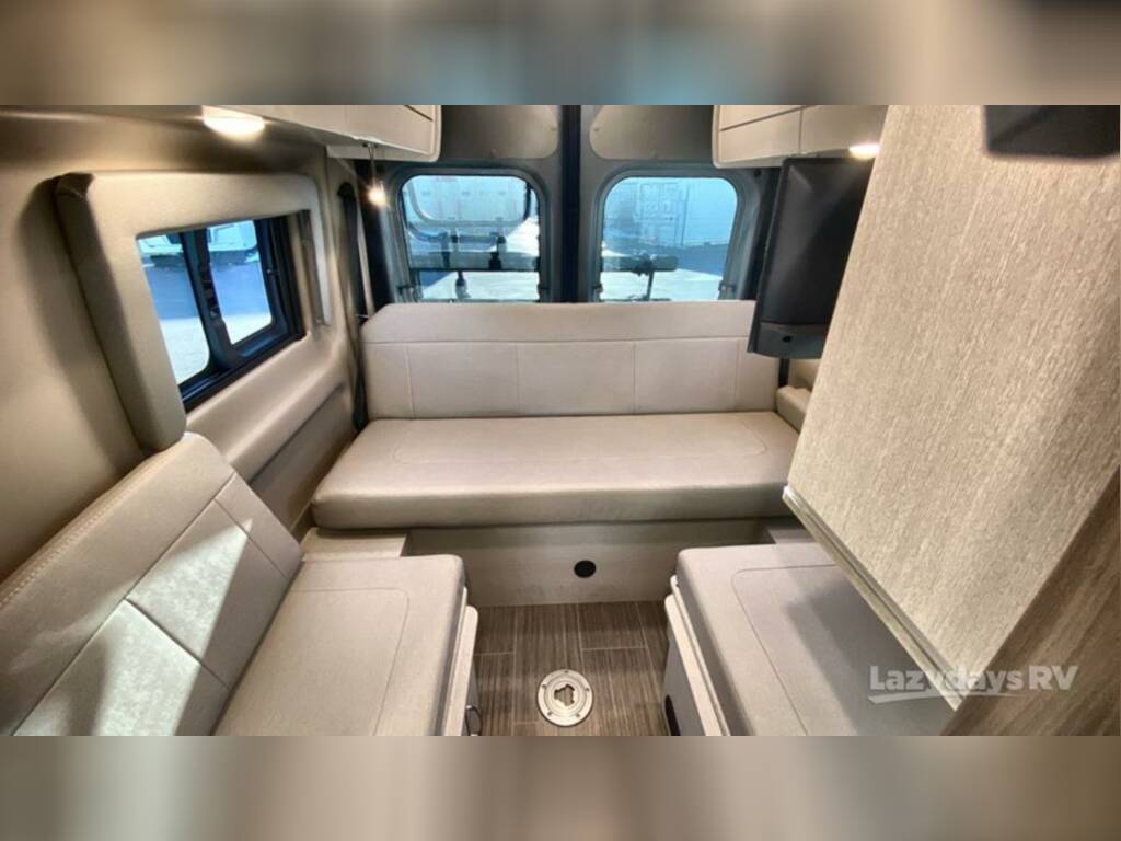 surrounded by lush trees and a white fence.|Compact RV rental wet bath with toilet — photo 12