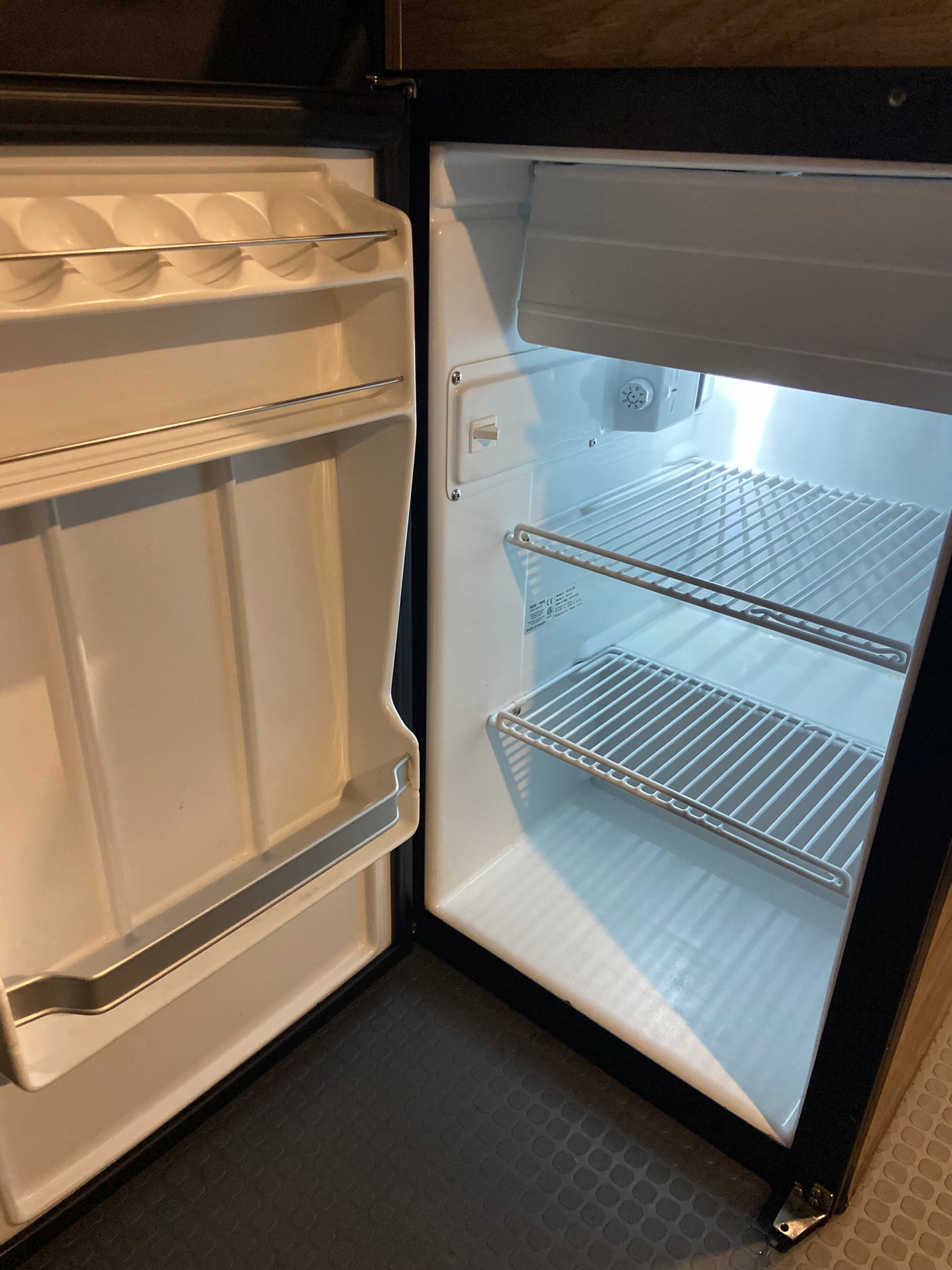 Inside the clean, empty mini-fridge of your RV rental, with wire shelves and door storage, ready for food and drinks.