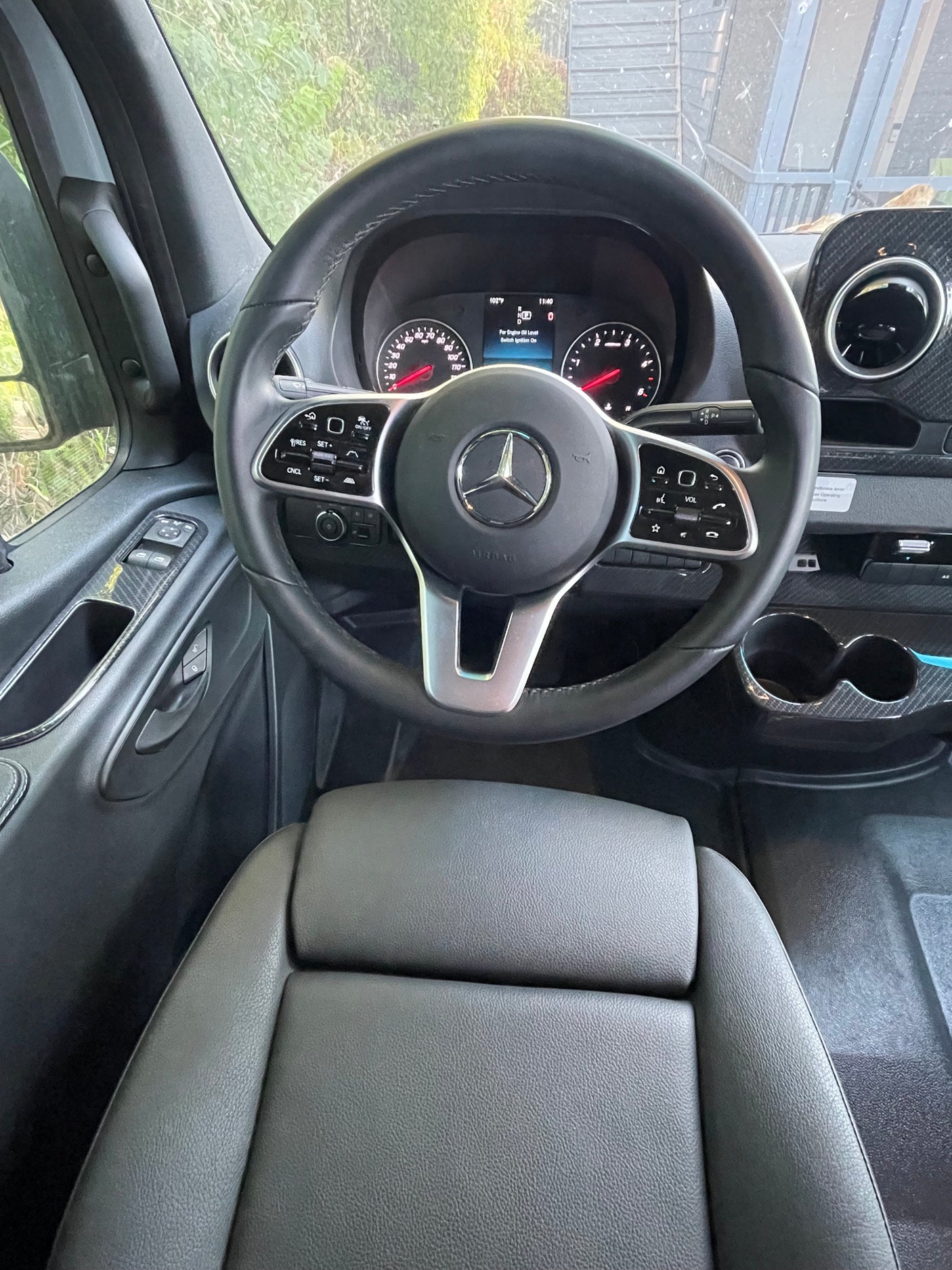 Driver's cockpit of a modern Mercedes-Benz van, possibly an RV rental, showing the dashboard and steering wheel.
