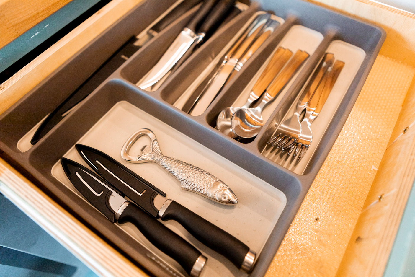 This organized RV rental kitchen drawer holds all the cutlery you'll need: knives, forks, spoons, and a fun fish bottle opener.