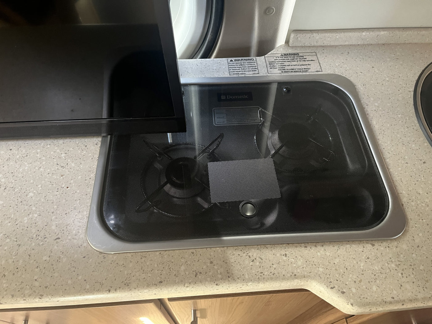 RV rental kitchen: Dometic two-burner cooktop with cover and warning labels on a light-colored counter. — photo 19
