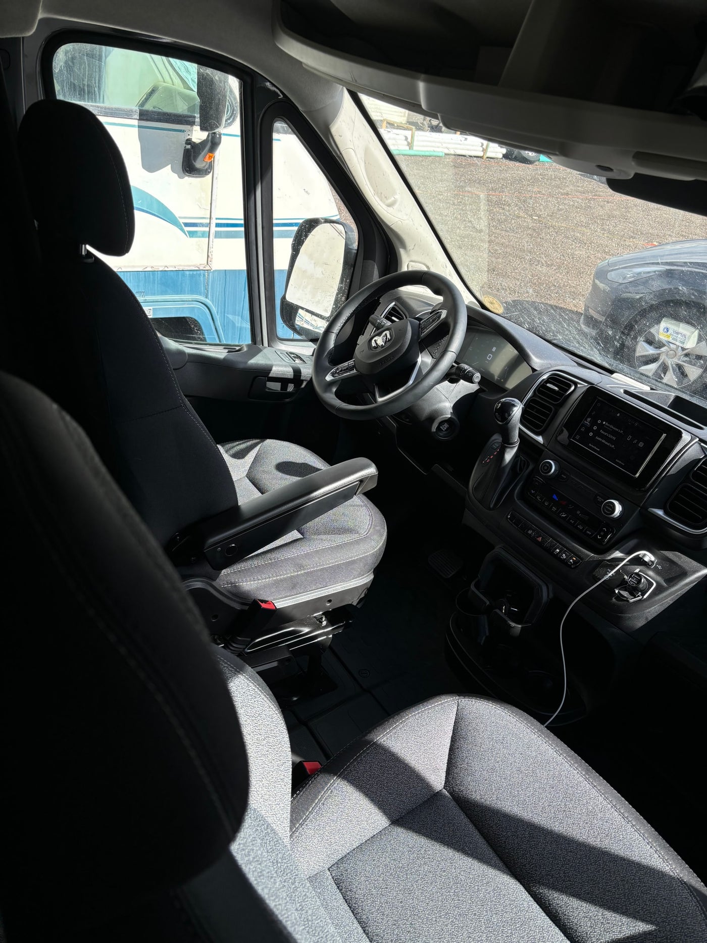 Inside a comfortable rv rental van, featuring the driver's cockpit, dashboard, and infotainment system, with an RV nearby. — photo 14