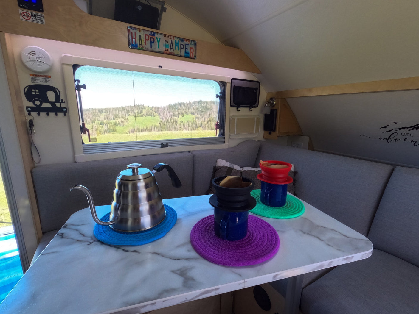 A cozy rv rental interior features a coffee pour-over setup on the table, with a stunning scenic window view for your travel adventure.