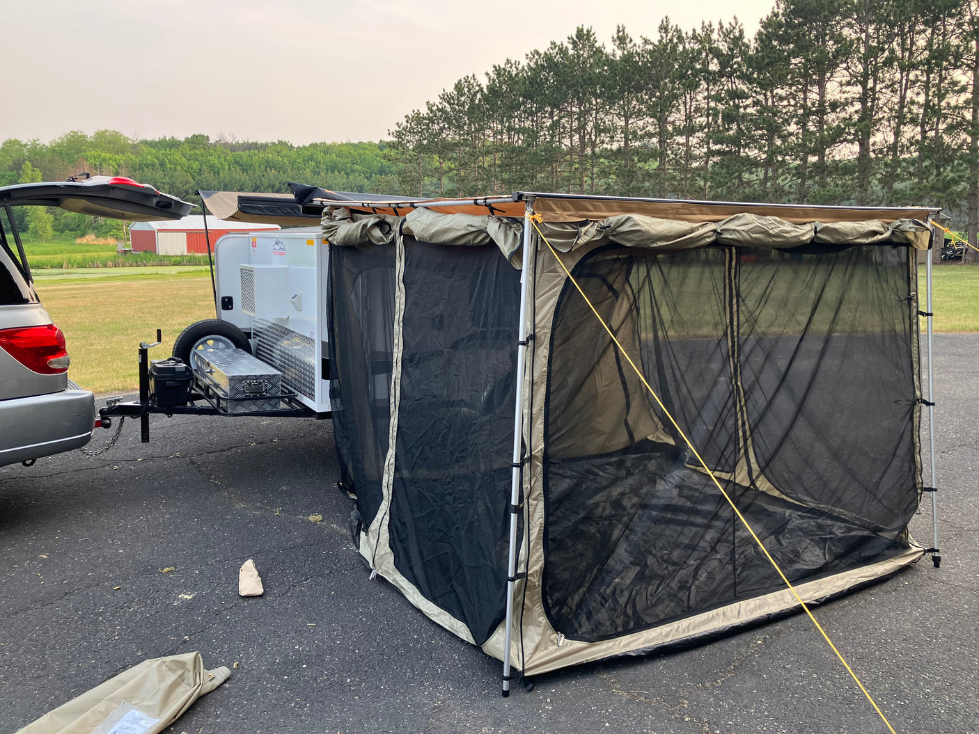 This rv rental setup features a compact travel trailer with an expansive screen room, perfect for outdoor camping comfort.