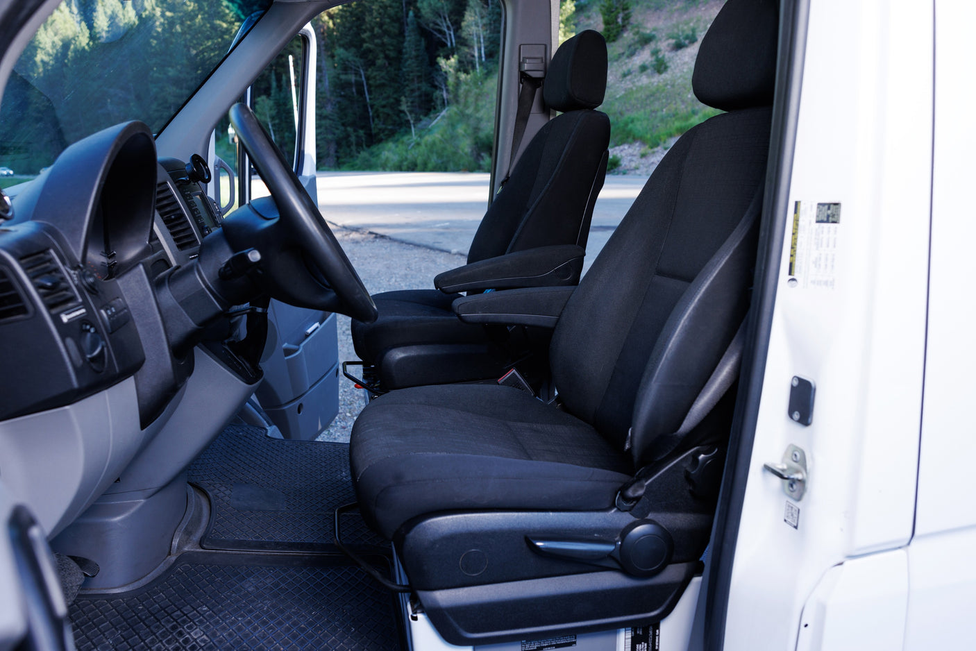 Interior of an RV rental van: driver and passenger seats, dashboard, and floor mats. Ready for your next adventure!