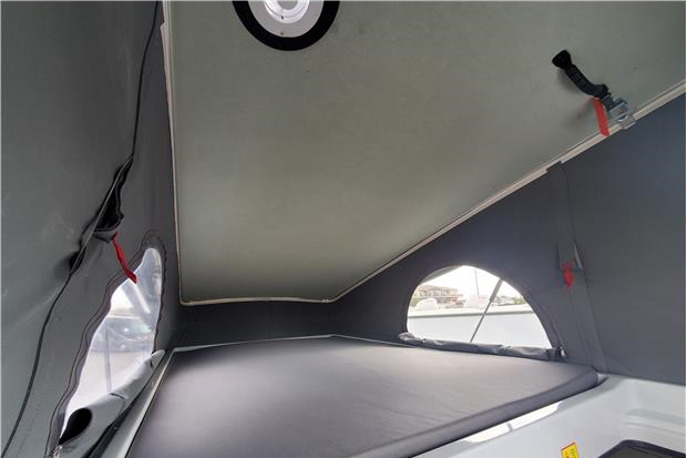 Explore your RV rental's pop-top sleeping area, featuring a comfortable bed, soft walls, and arched windows.