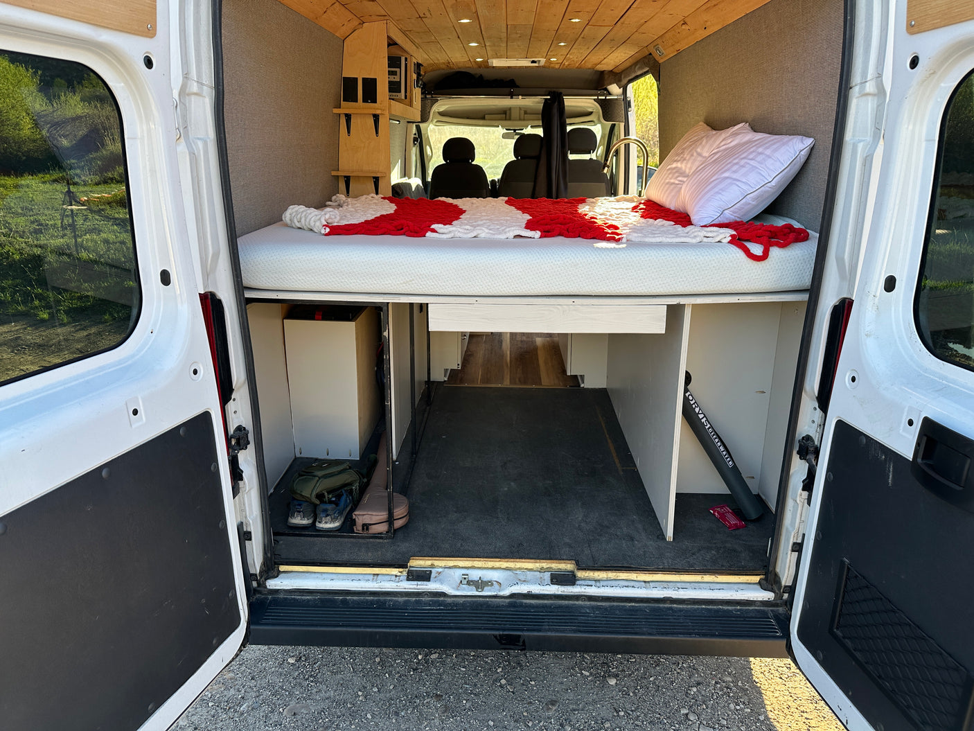 Inside this customized RV rental: a raised bed, spacious cargo area, and built-in storage. Ready for adventure!