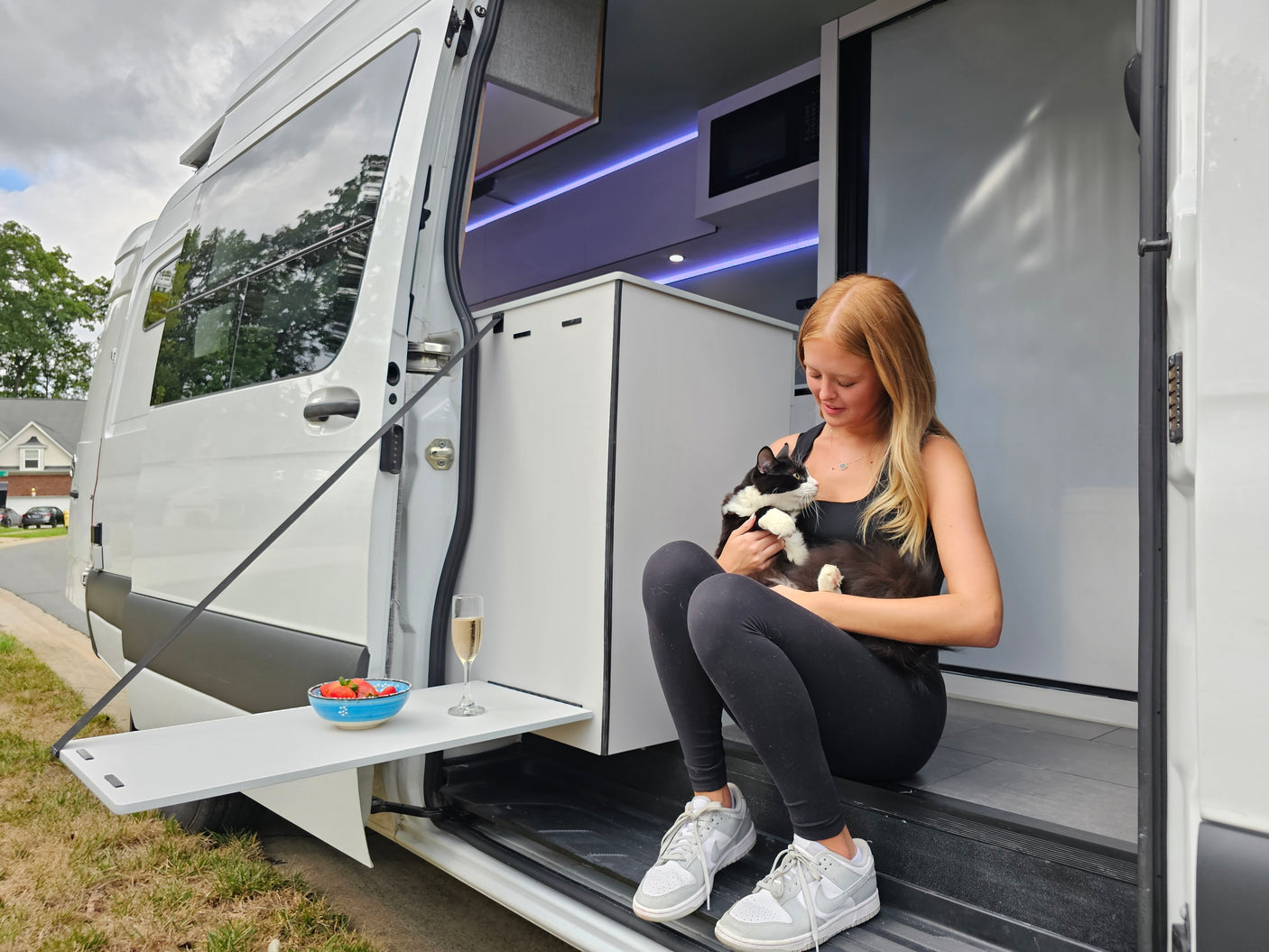 Enjoy a modern RV rental, featuring a woman and her cat enjoying the comfortable interior with an extendable outdoor table.