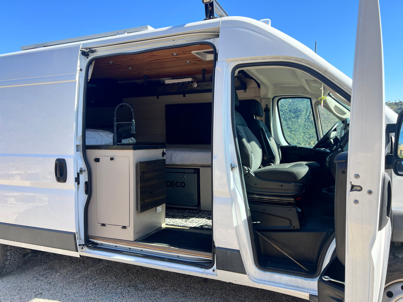 This white rv rental showcases its well-equipped interior with kitchen, bed, and front seats, ready for adventure.