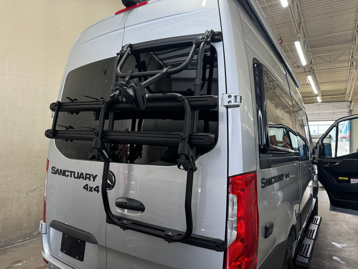 Silver Mercedes-Benz Sanctuary 4x4 camper van with a bike rack, ideal for an RV rental.