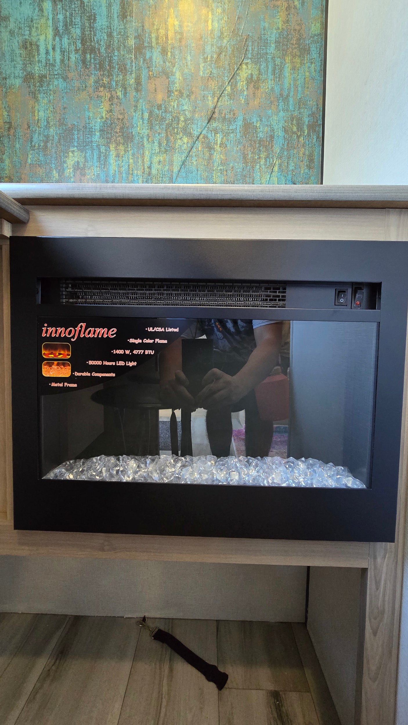 Modern Innoflame electric fireplace, a cozy amenity in this RV rental. Features glass "ice" media and an abstract art backdrop.