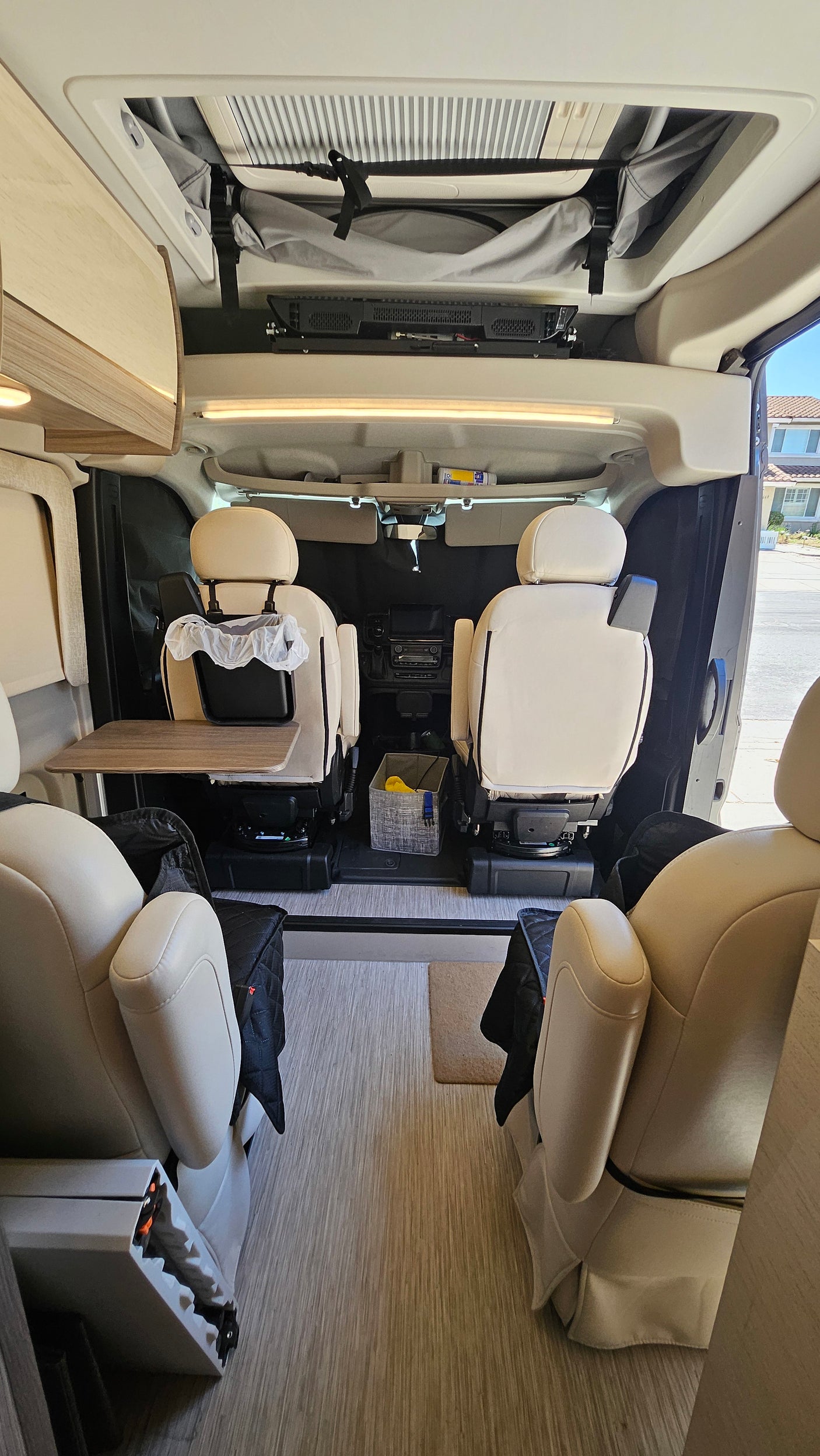 This **rv rental** camper van interior features swiveled front seats, a movable table, and convenient overhead storage.