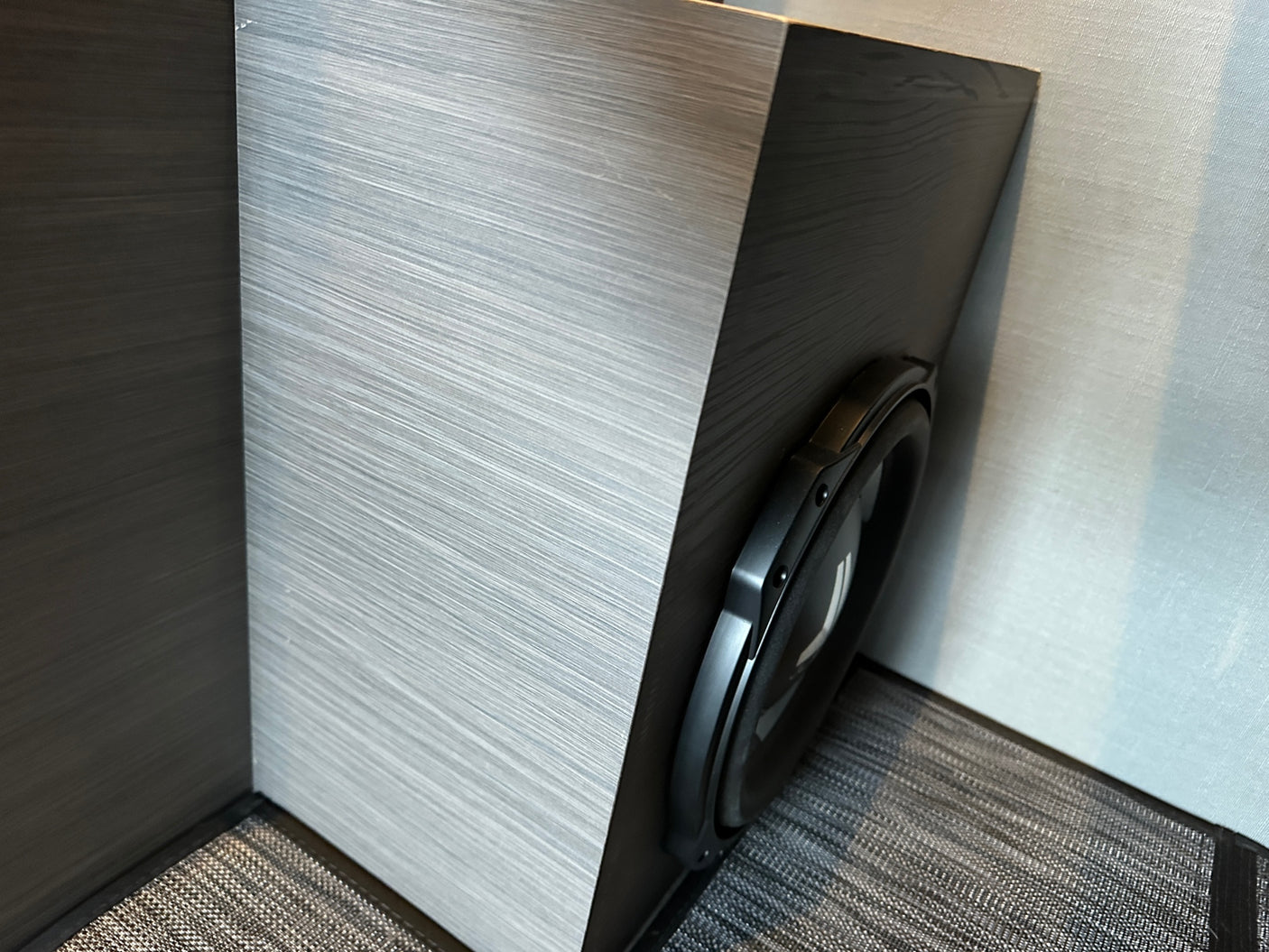 Modern **RV rental** interior with a large subwoofer neatly integrated into sleek, two-toned textured cabinetry.