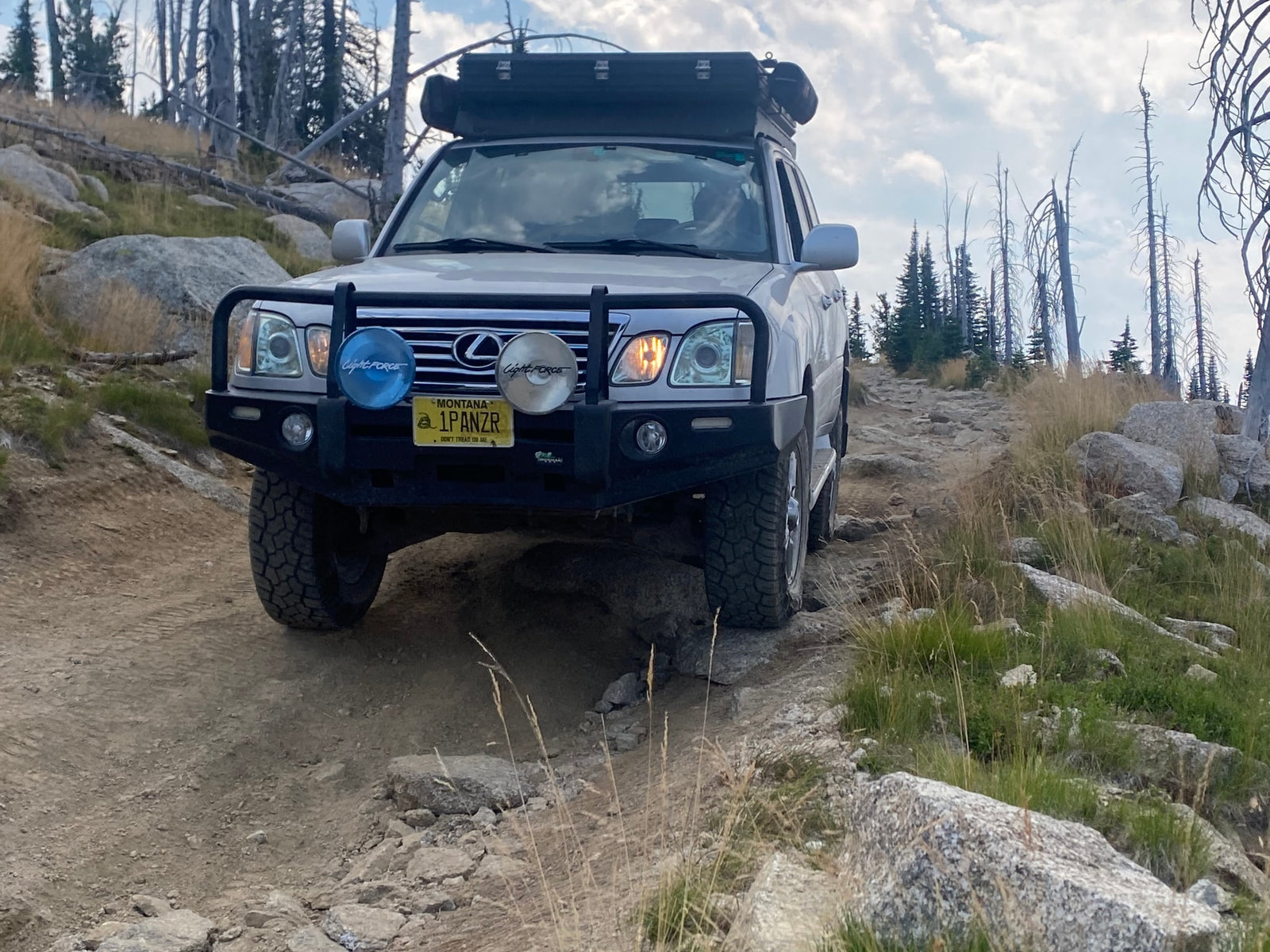 and a compact audio system.|This rugged MISSION OVERLAND Limited pop-top trailer is ready for your next RV rental adventure in a snowy forest.|An overlanding SUV with rooftop tent & awning by a river in a dense forest