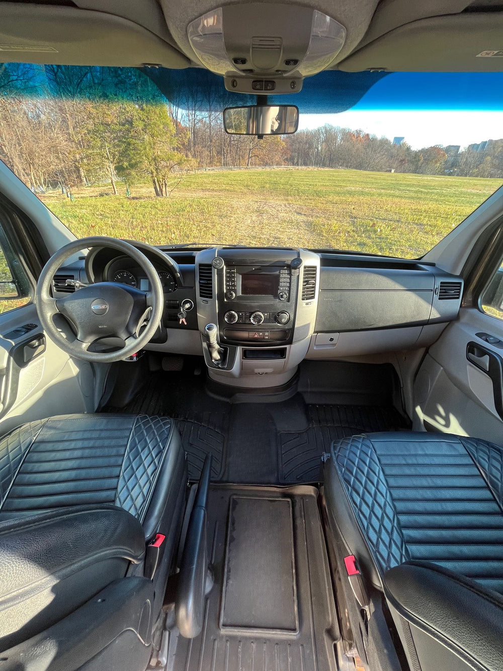 equipped for adventure with a roof rack and ladder. Perfect for your next RV rental.|Open rear doors of a dark grey **rv rental** camper van reveal a cozy bed & storage. Parked on dry grass.|Step inside this modern RV rental camper van