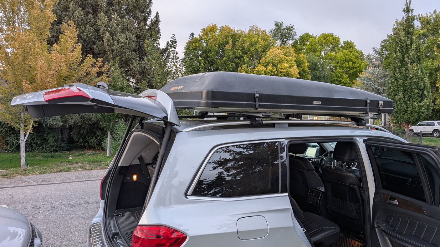 This silver SUV, with an open trunk and roof cargo box, is prepped for travel, similar to an rv rental adventure.