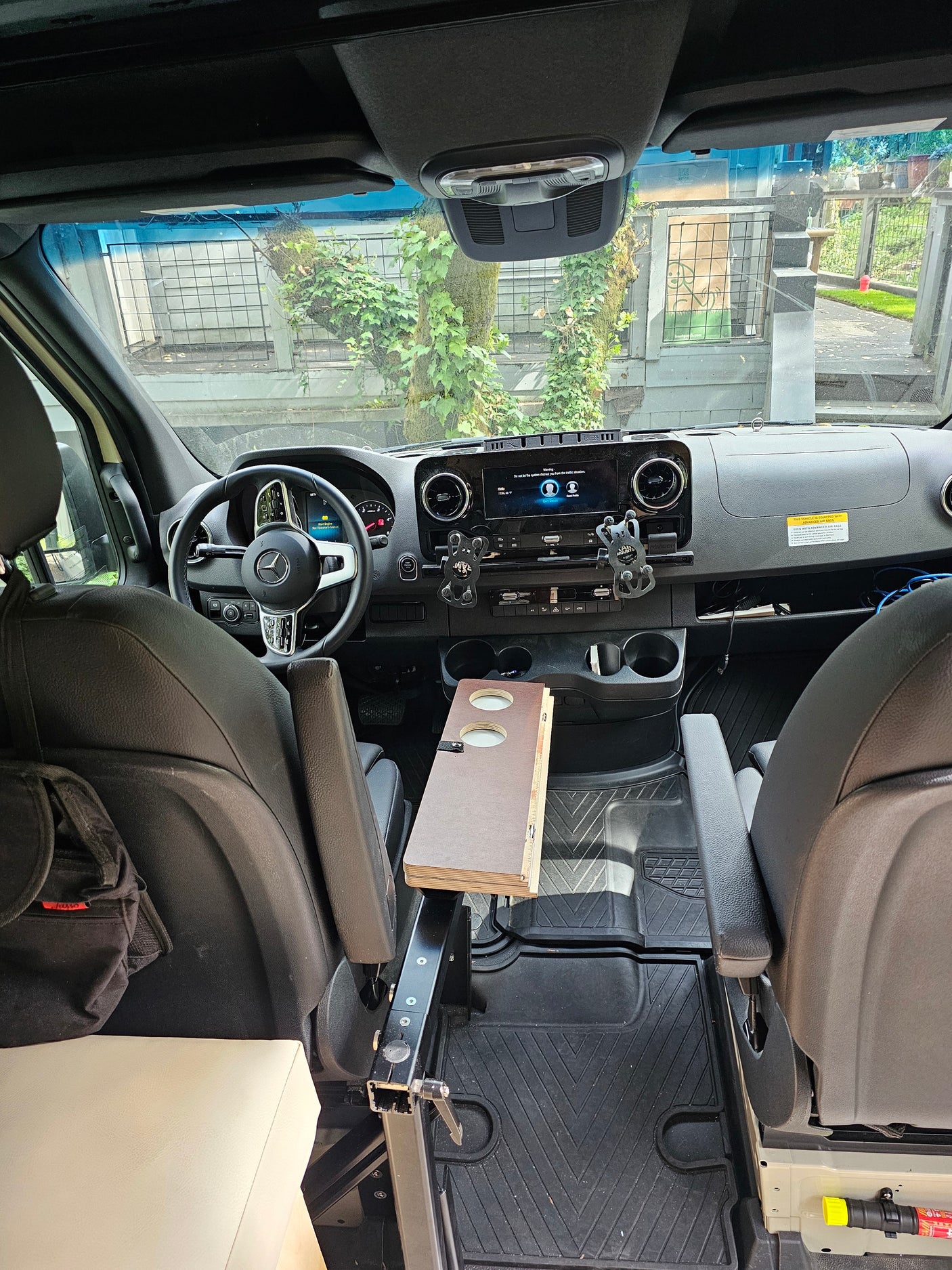 RV rental camper van interior: modern dashboard, swiveled front seats, and a custom table. View from the back cabin.