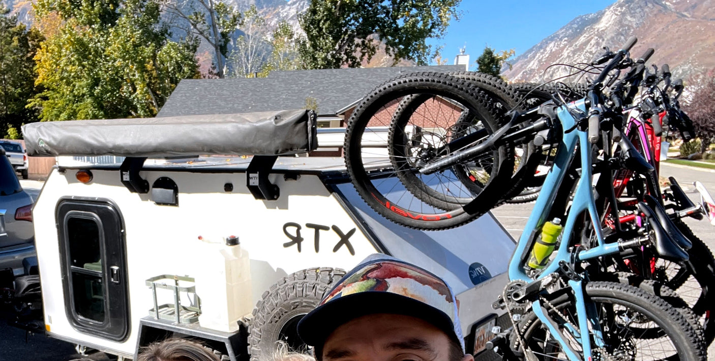 White RTX overland camper, loaded with bikes for mountain adventures. A perfect RV rental for outdoor trips.