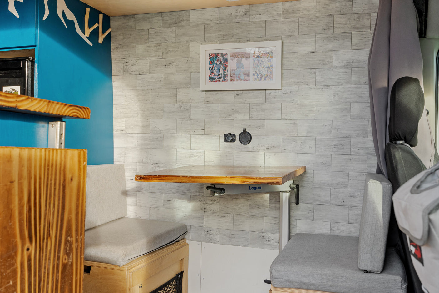 Inside an RV rental: a flexible dining space with a Lagun table, comfy bench seats, and stylish wood-paneled walls.