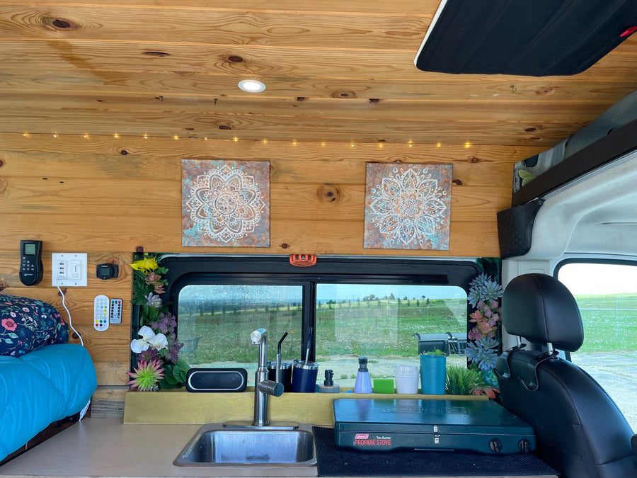 Cozy RV rental interior with compact kitchen, bed, and scenic views for comfortable travel adventures.