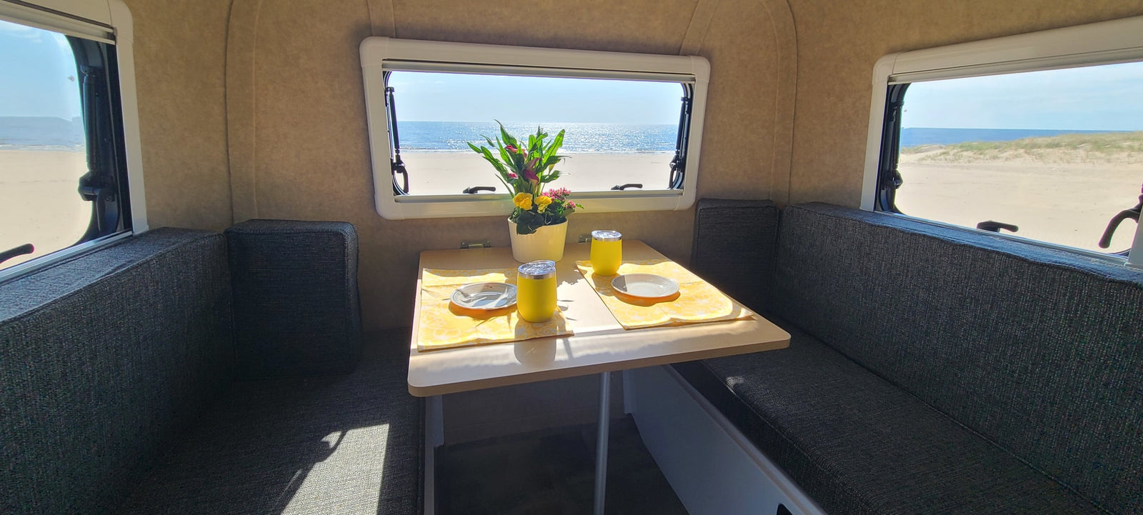 Enjoy stunning beach views from this cozy RV rental dining area, set for a meal in paradise.