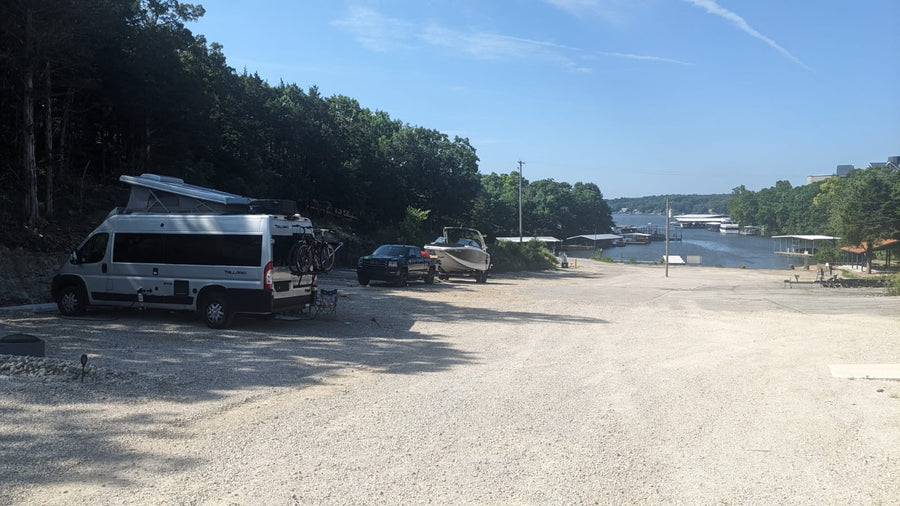 facing iconic red rock formations. Perfect desert travel.|This RV rental and boat are parked on a sunny gravel lot