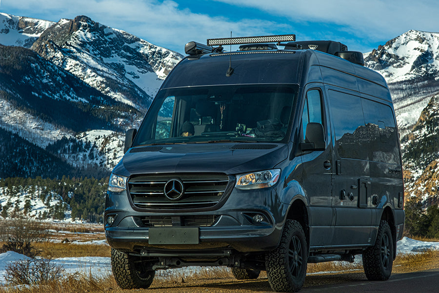This dark grey Mercedes Sprinter **RV rental** with off-road tires is perfect for mountain adventures.