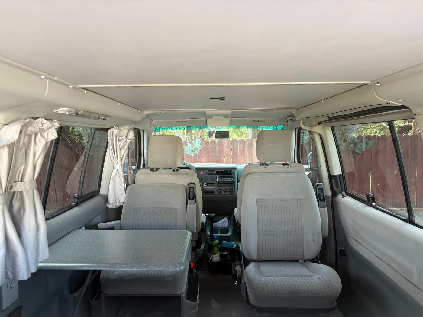 RV rental interior: Looking forward from the back, featuring front seats, a side table, and privacy curtains. — photo 5